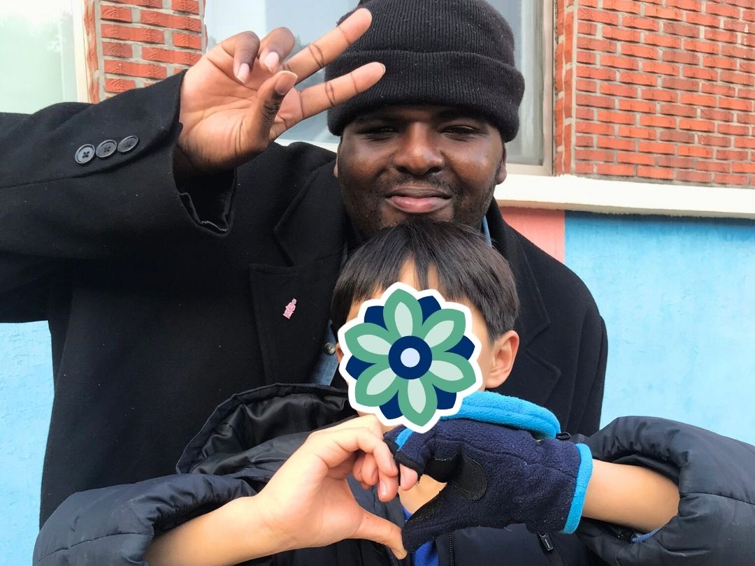 Volunteer posing outside for a photo with a child during a KKOOM visit.