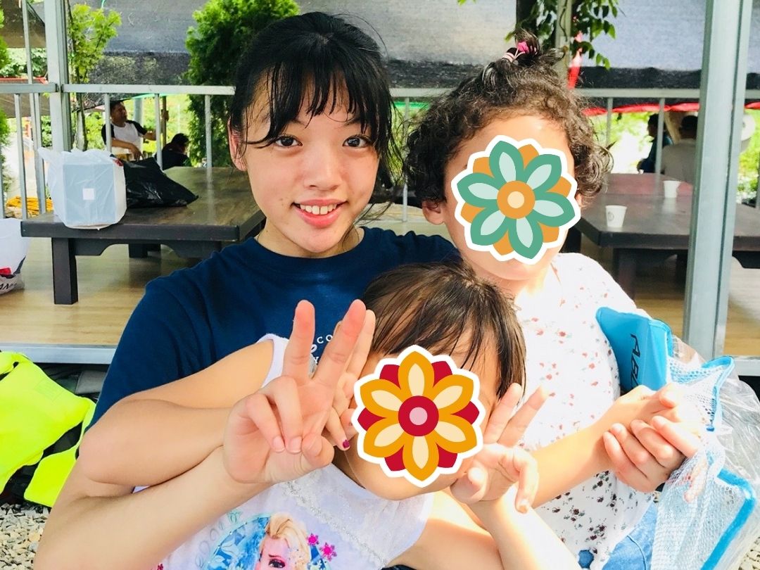 Teacher and students smiling together outdoors during a KKOOM activity.