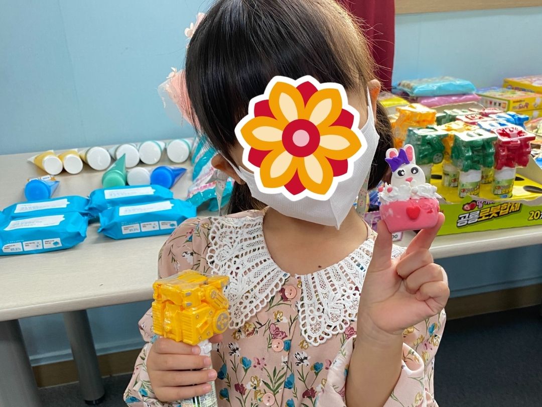 Child holding a holiday craft and treats during a KKOOM program event.