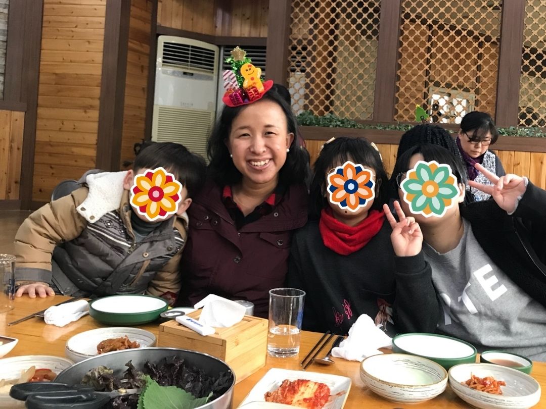 Grace sharing a meal with children during a KKOOM holiday gathering.