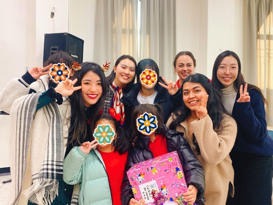 Volunteers and youth holding gifts at a KKOOM holiday event.