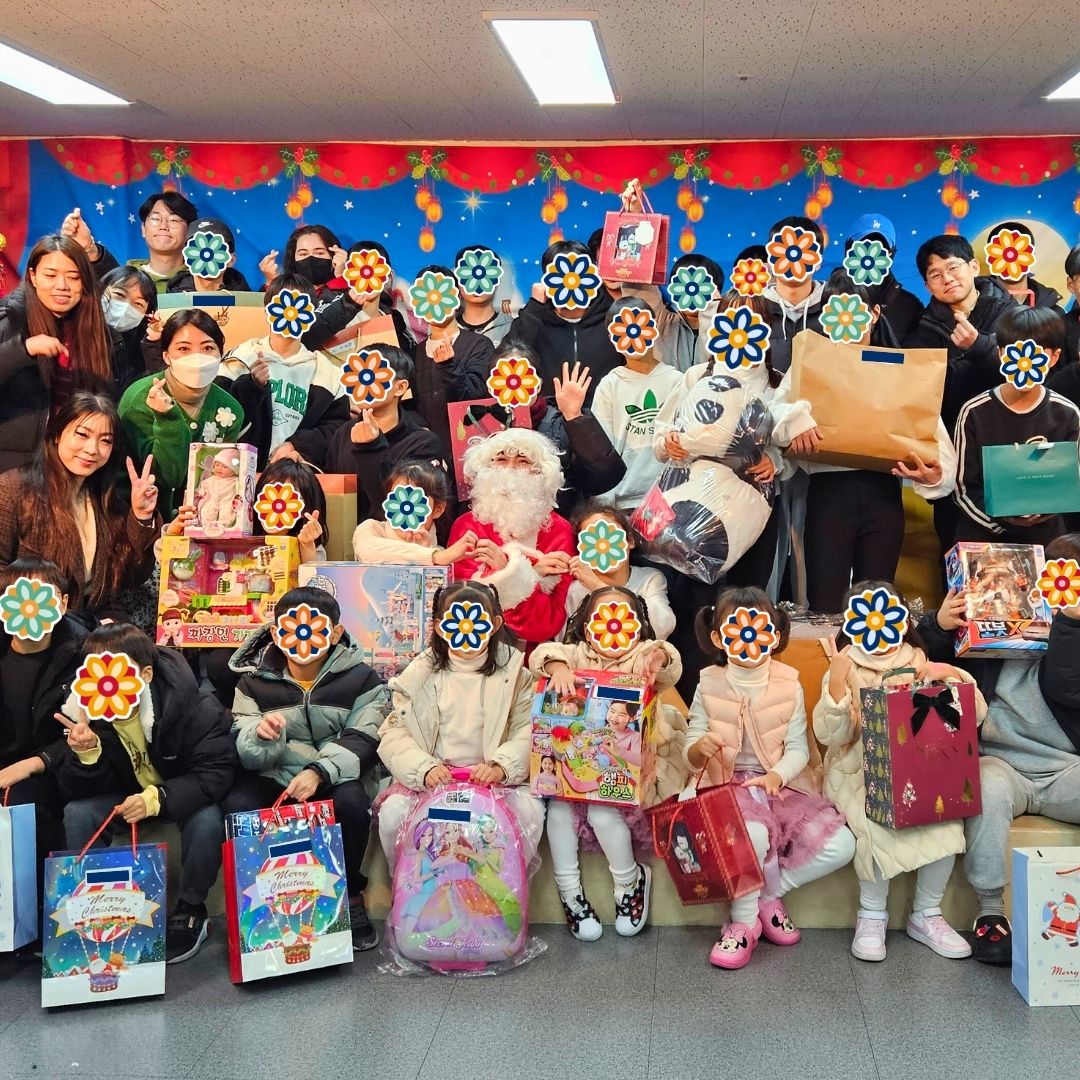 Large group of children and volunteers gathered for a festive holiday celebration at a KKOOM event.