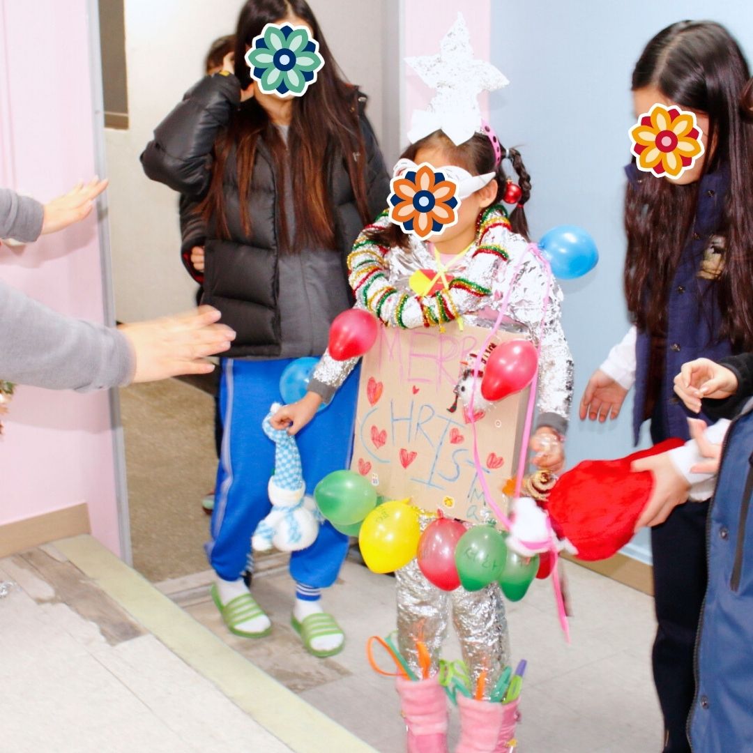 Child wearing a festive costume of balloons as part of a holiday party game.