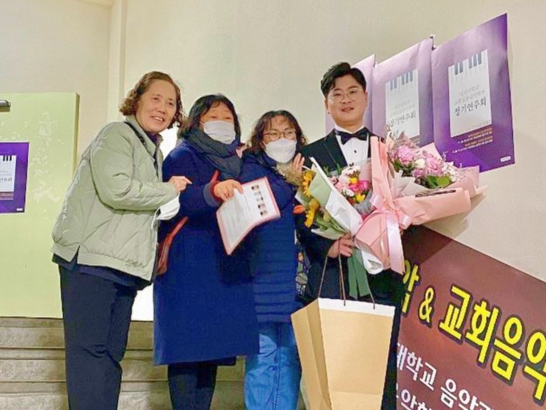 KKOOM Scholarship recipient holding flowers with children's home staff.