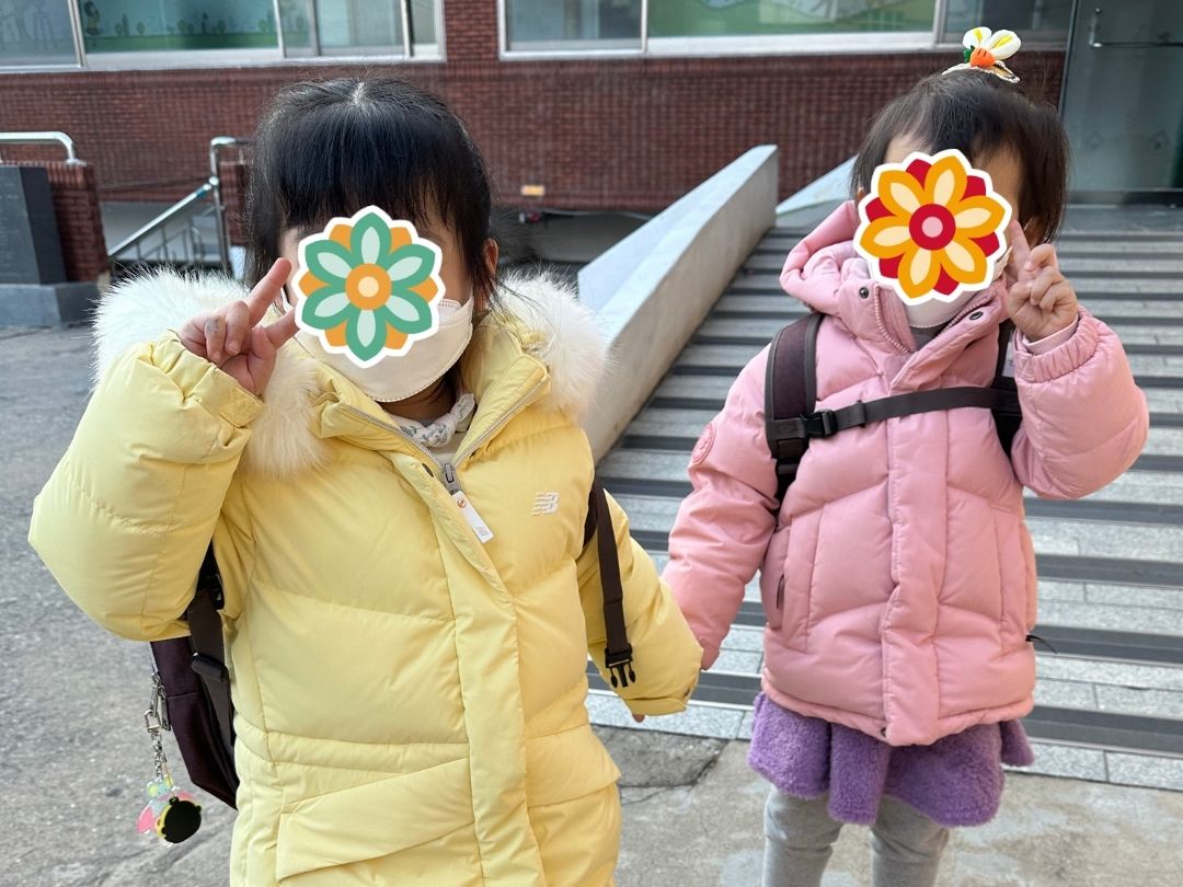 Two young students wearing backpacks and winter coats while leaving school.