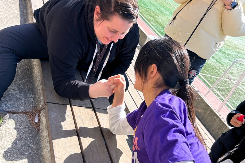 Margaret shares a playful arm-wrestling moment with a girl during the program.